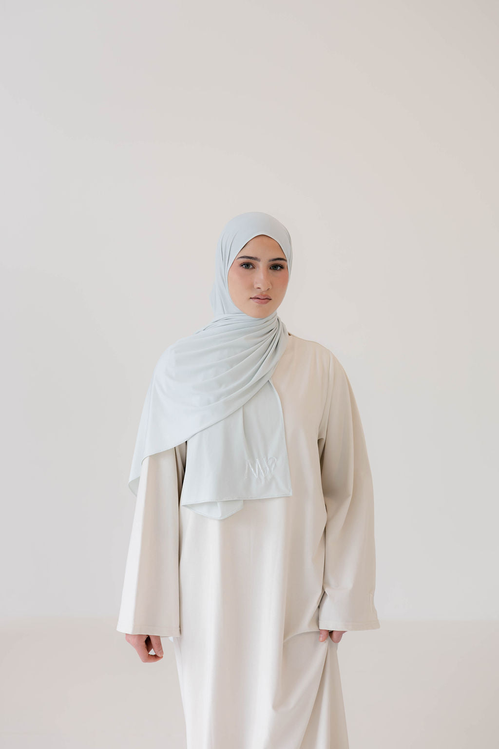 Model wearing eco-friendly abaya dress made of Sorona bio-cotton, lightweight and breathable material in color off white and ice white premium jersey scarf naleya wear