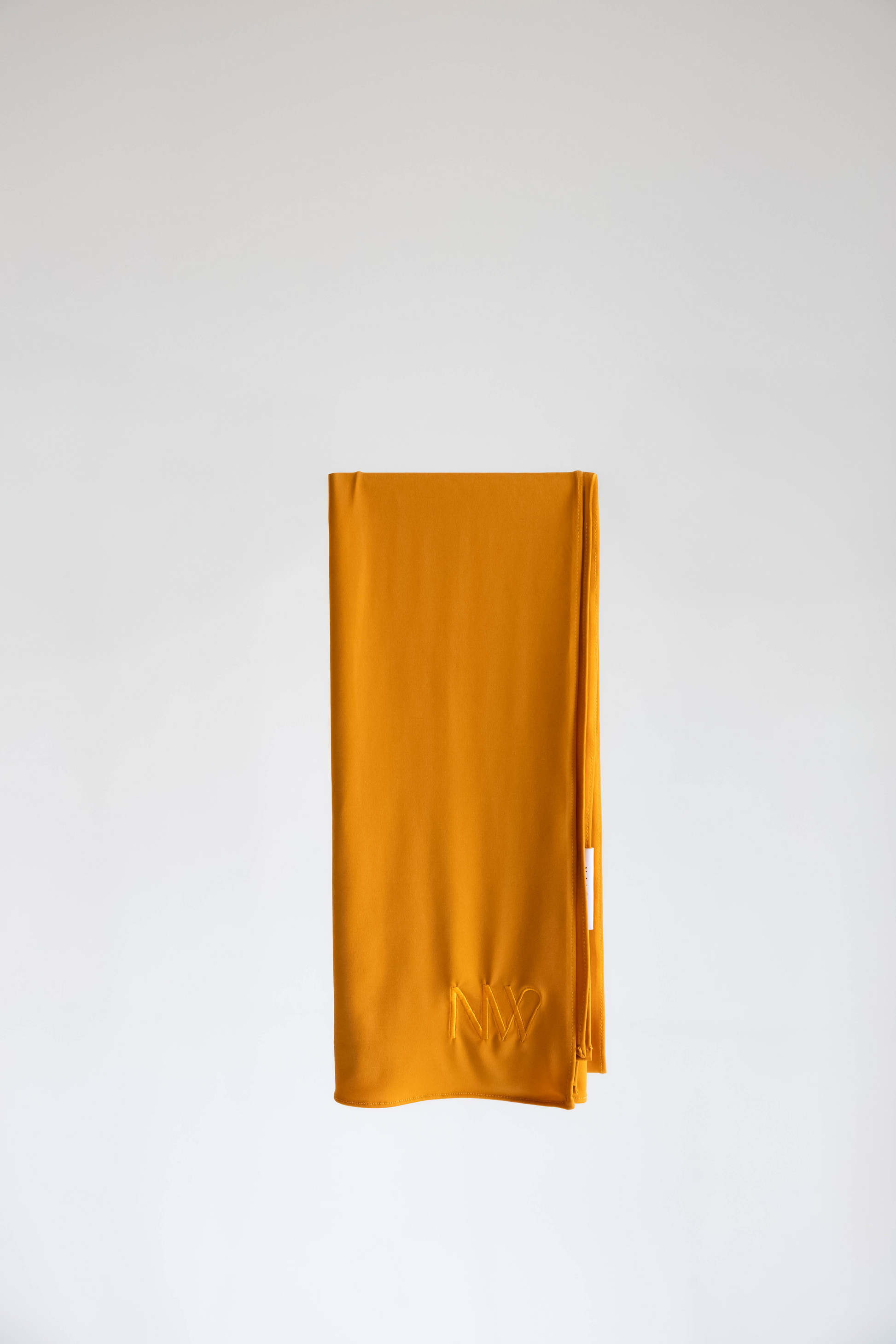 Premium jersey hijab in mustard yellow by Naleya Wear, folded and displayed on a neutral background