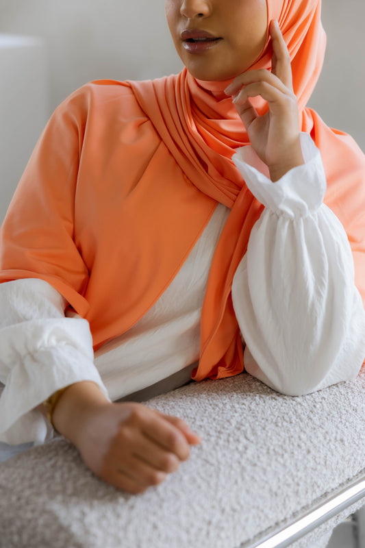 Model wearing a premium jersey hijab in orange color by Naleya Wear