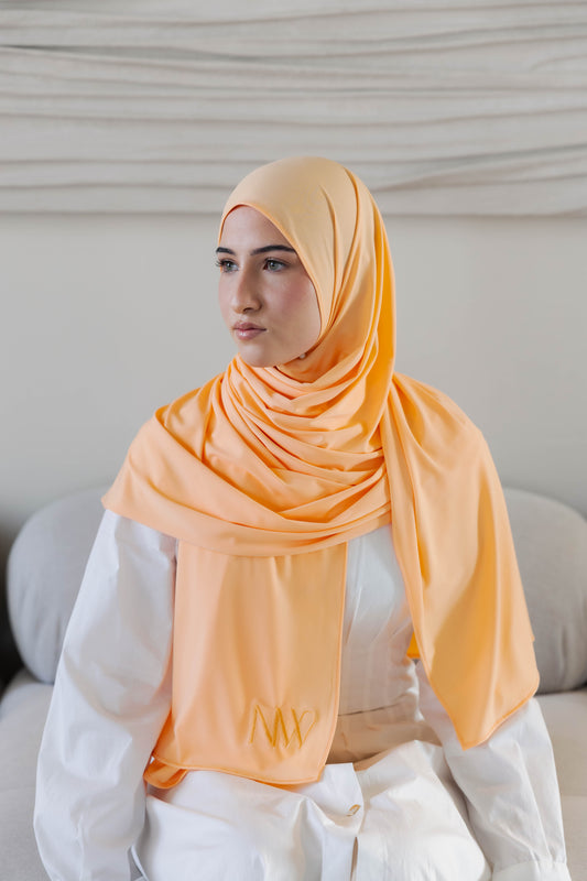 Model wearing a premium jersey hijab in pastel orange color by Naleya Wear